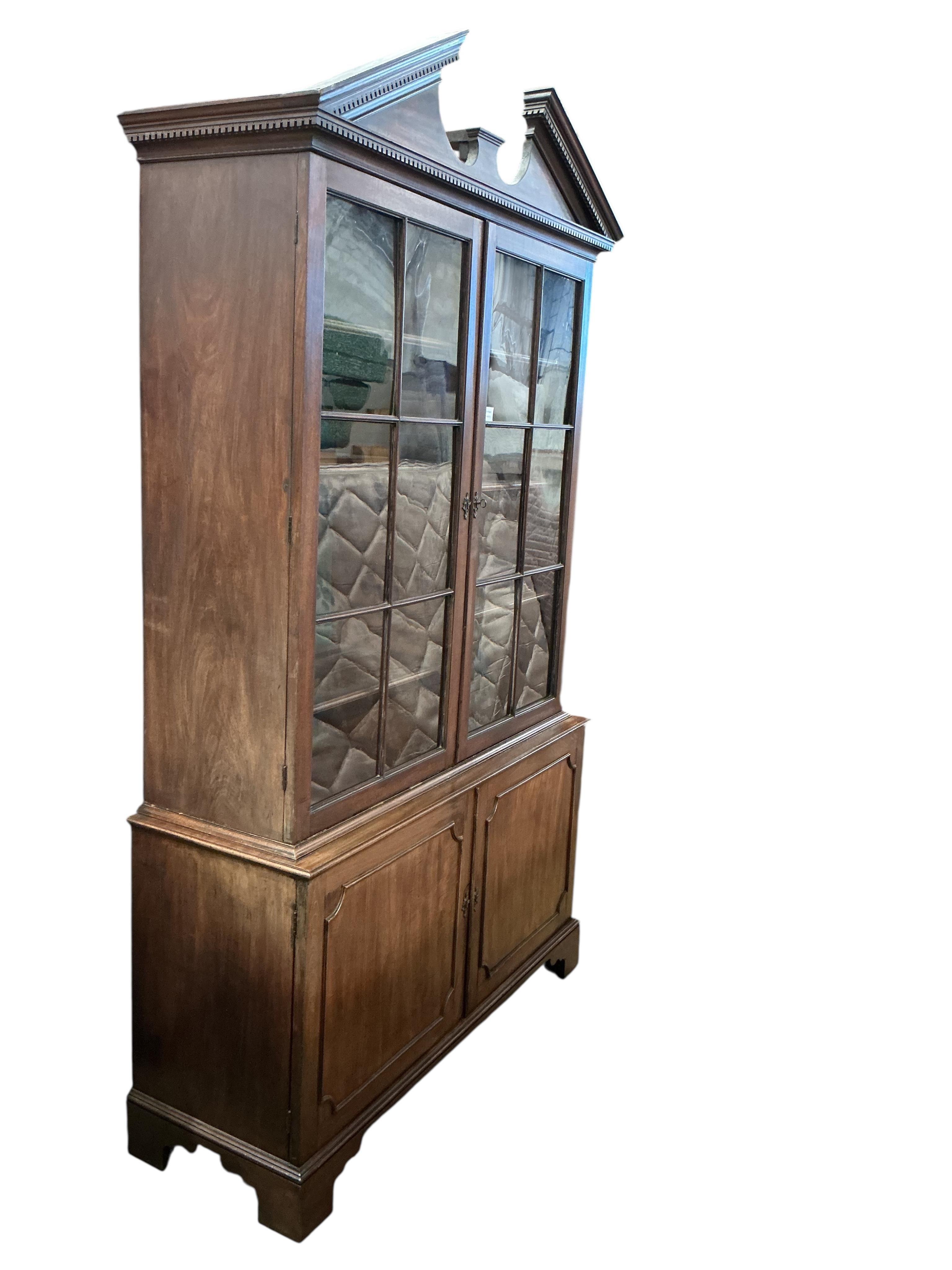 A George III mahogany library bookcase, the top surmounted with a broken architectural pediment, width 132cm, depth 47cm, height 234cm